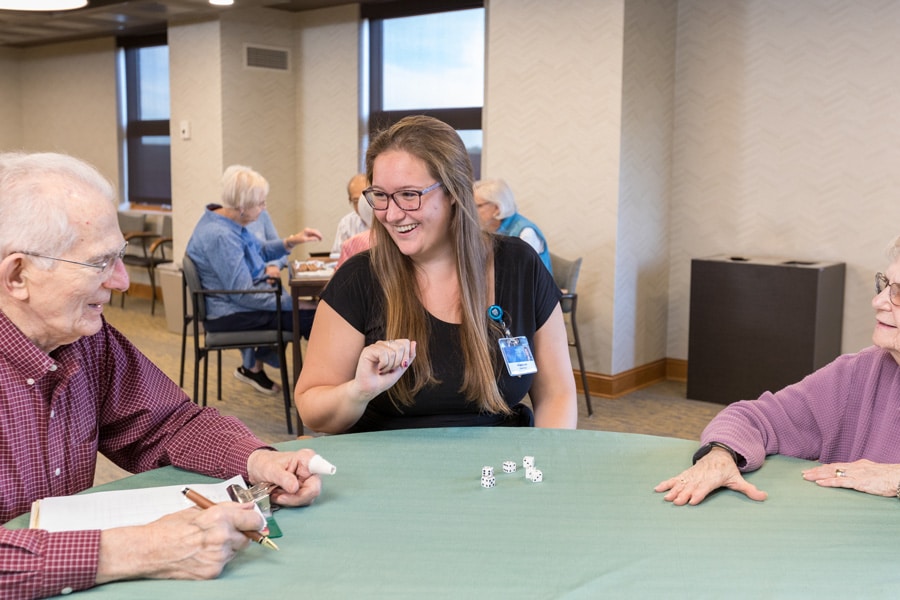 Female Employee Smiling While Playing Dice With Residents