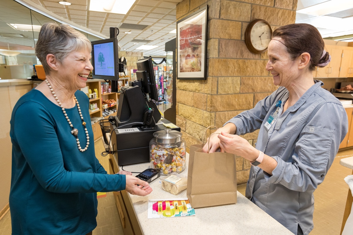 Woman Working In Convenience Store Bagging Residents Purchases