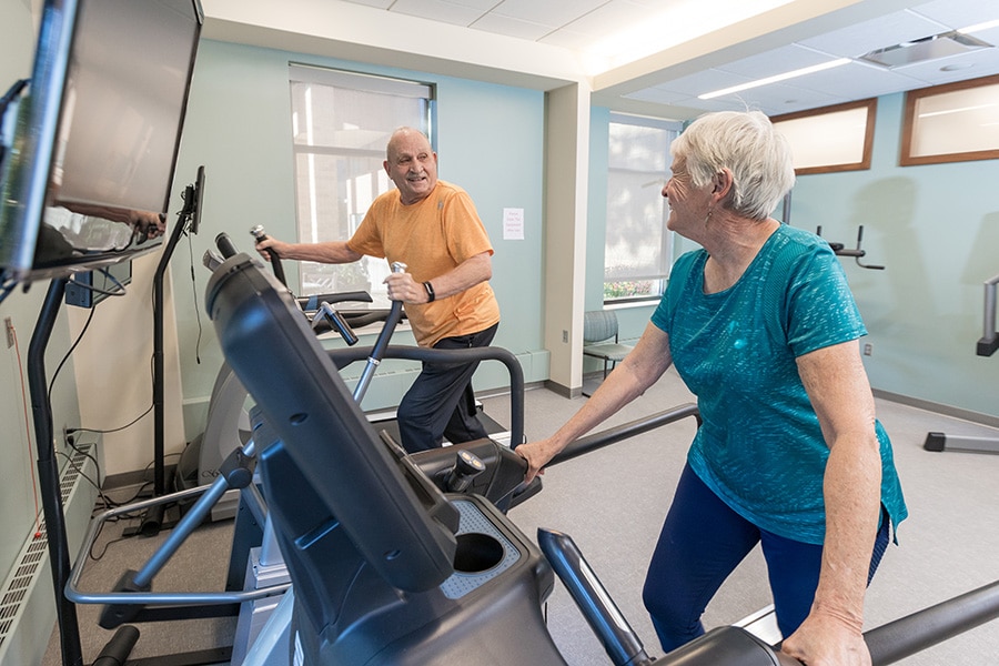 Elderly Man And Woman Walking On Fitness Machine