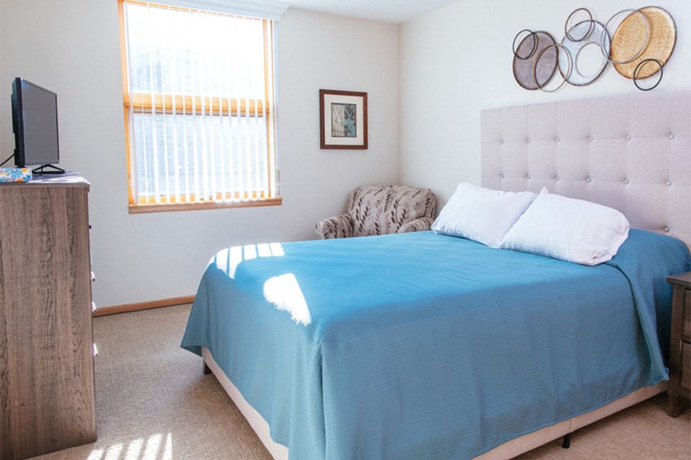 Bedroom with upholstered headboard and blue blanket