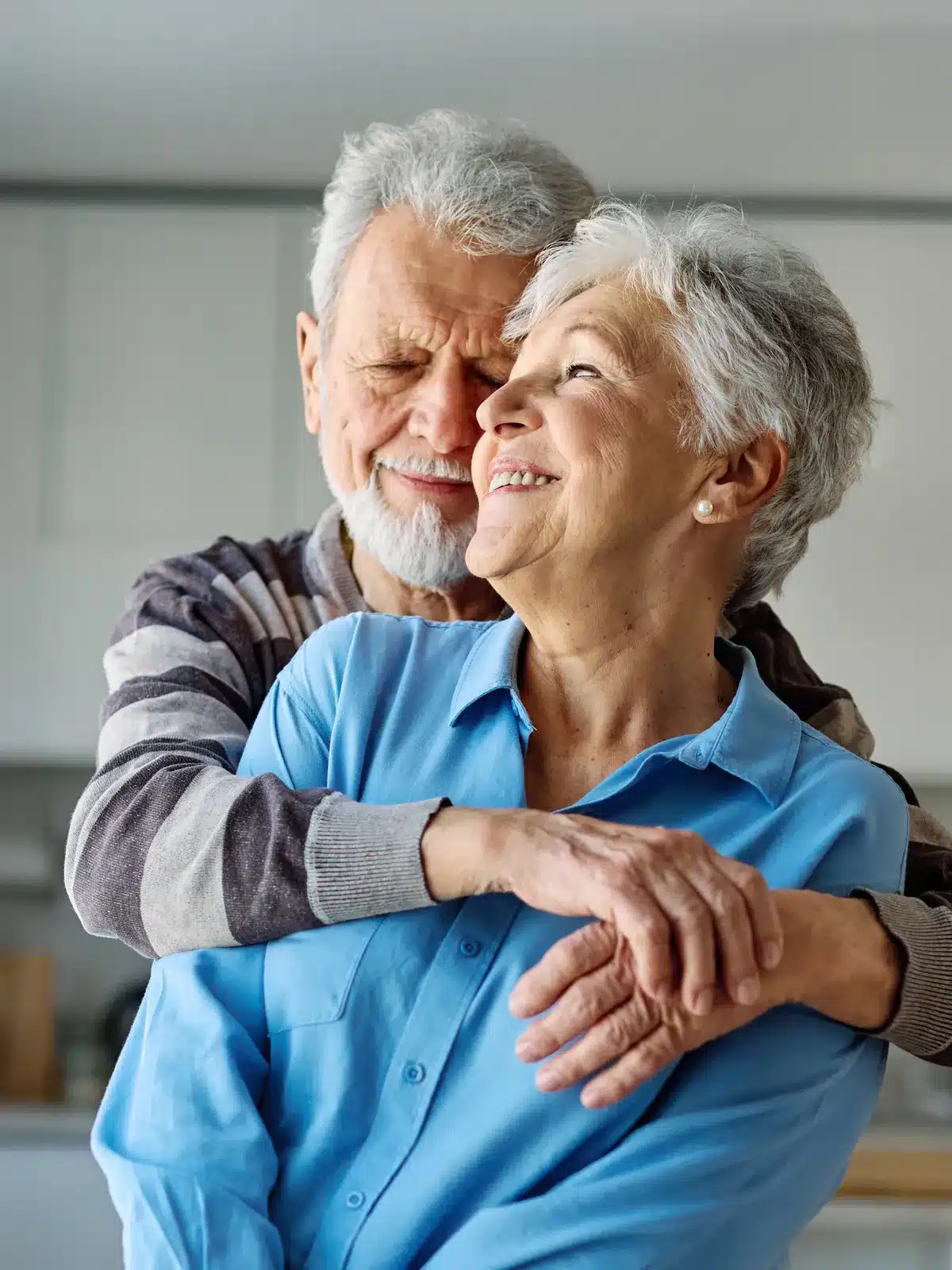 Elderly Couple Embracing In Kitchen Elderly Couple Embracing In Kitchen
