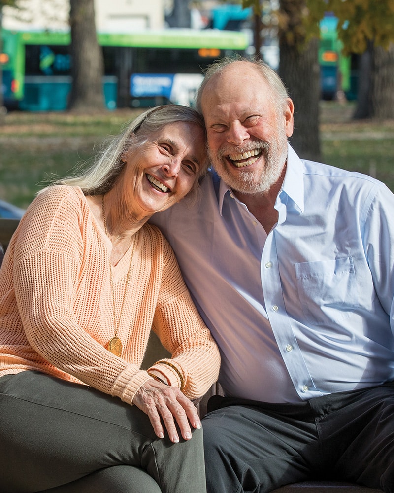 Happy Couple Sitting On Bench Outside