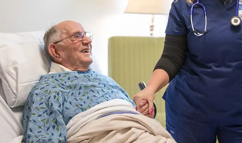 Resident Holding The Hand Of Charter House Nurse
